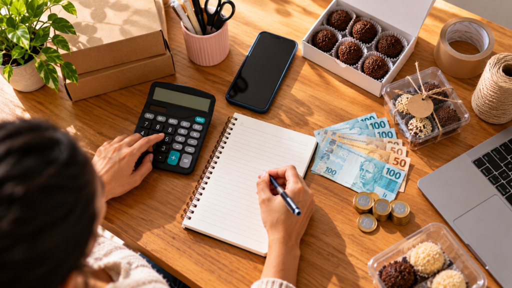 Pessoa calculando custos e organizando materiais para iniciar uma renda extra com baixo investimento.